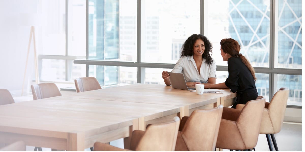 Two women using a laptop in a boardroom